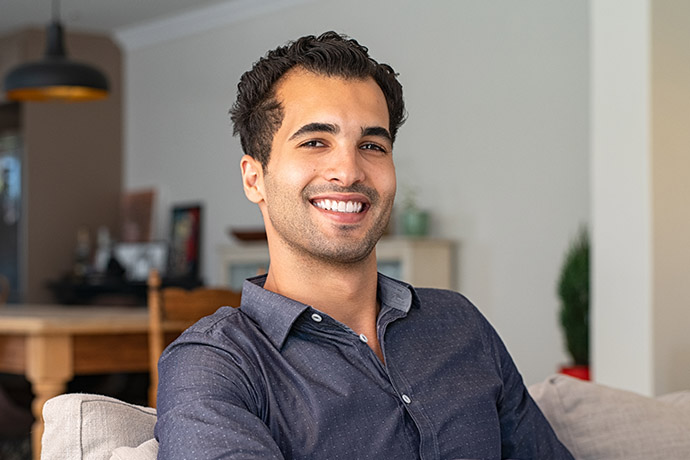 Happy young indian man at home-690x460